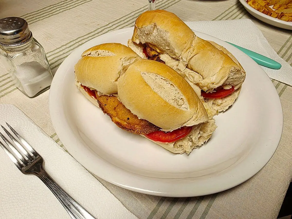 Sándwiches de pollo con tomate en pan francés servidos en un plato blanco