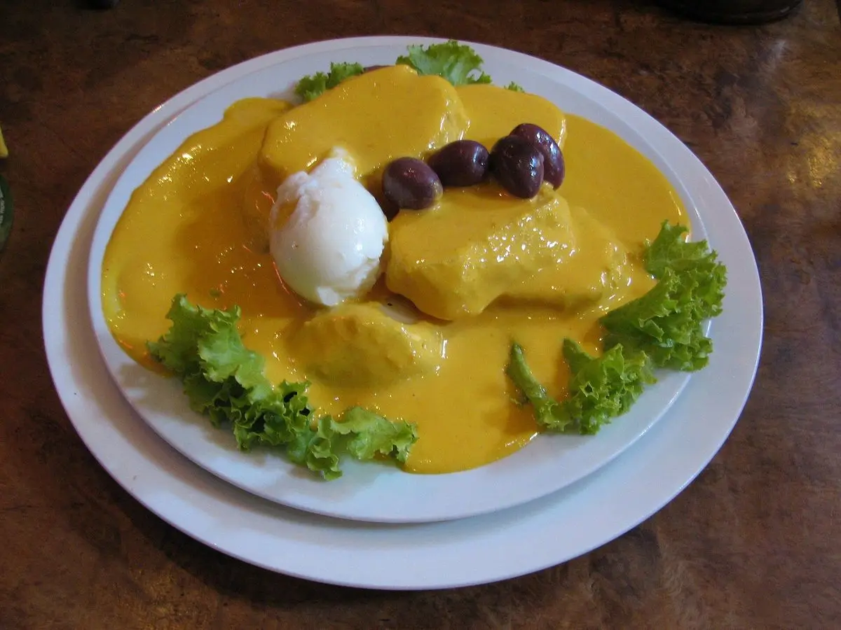 Papa a la huancaína, patata con salsa amarilla de queso, huevo duro y aceitunas moradas sobre lechuga