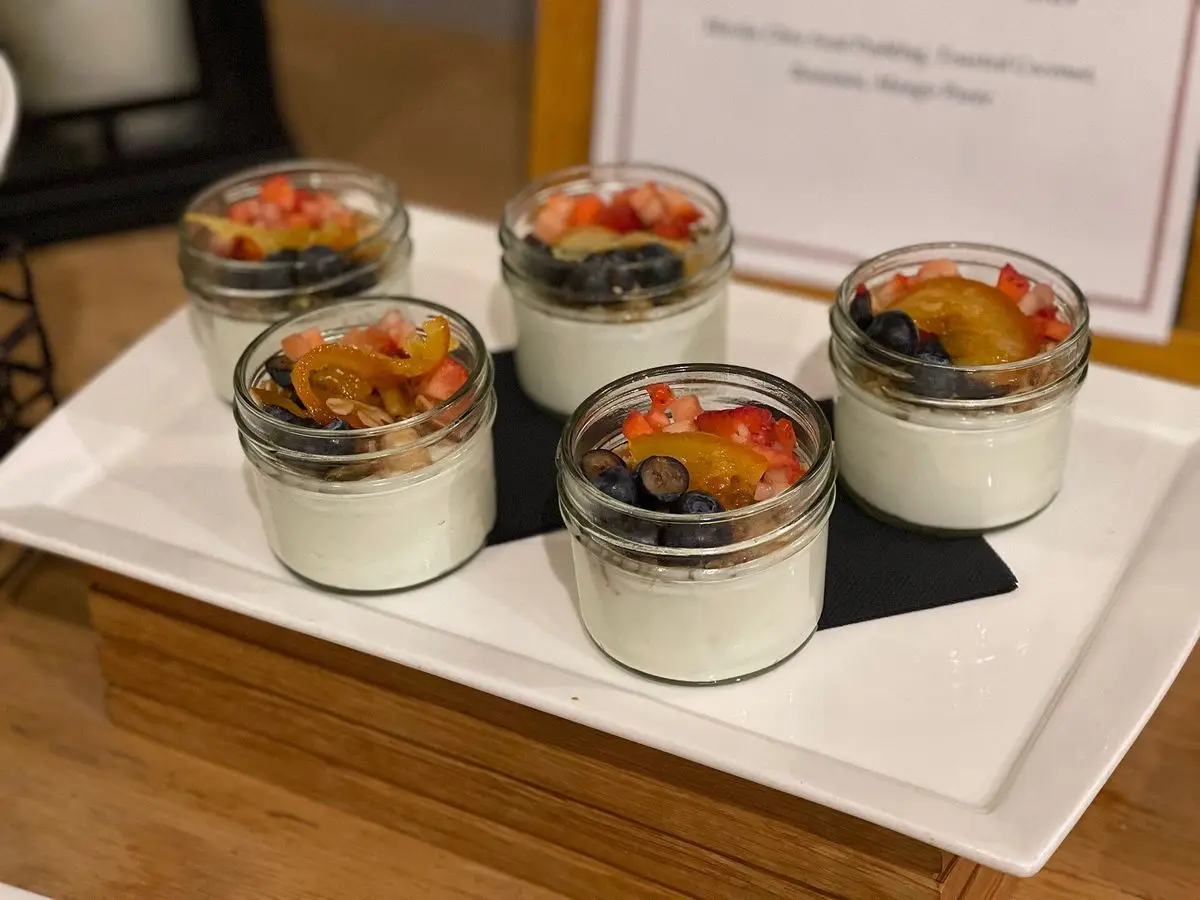 Cuatro tarros de cristal con yogur cremoso y compota de fruta sobre una bandeja blanca