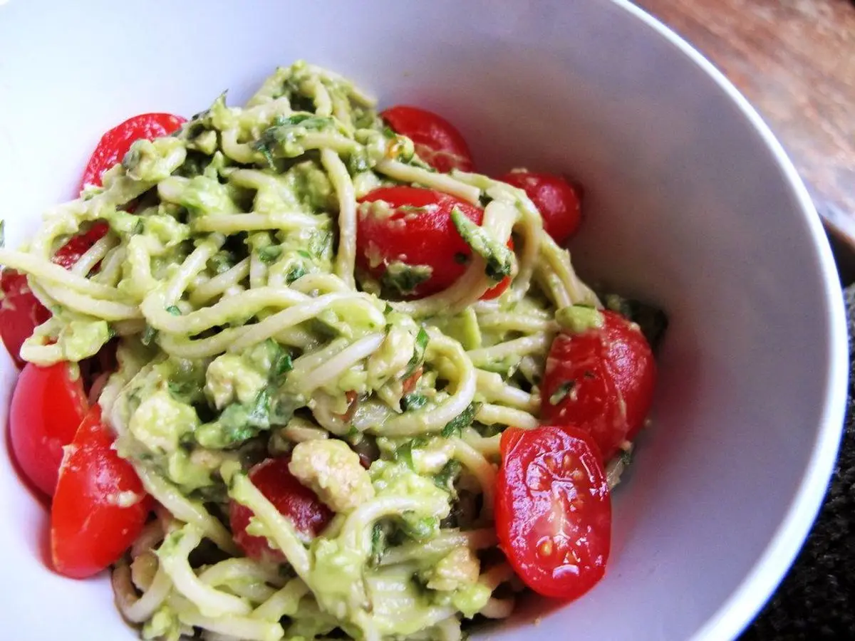 Cuenco blanco de pasta con pesto verde y tomates cherry