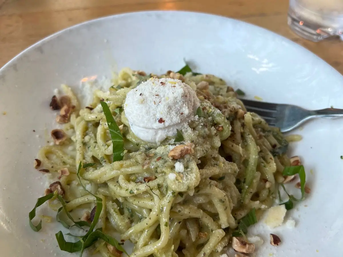 Espaguetis con salsa verde, una bola de queso fresco, avellanas troceadas y hojas de albahaca