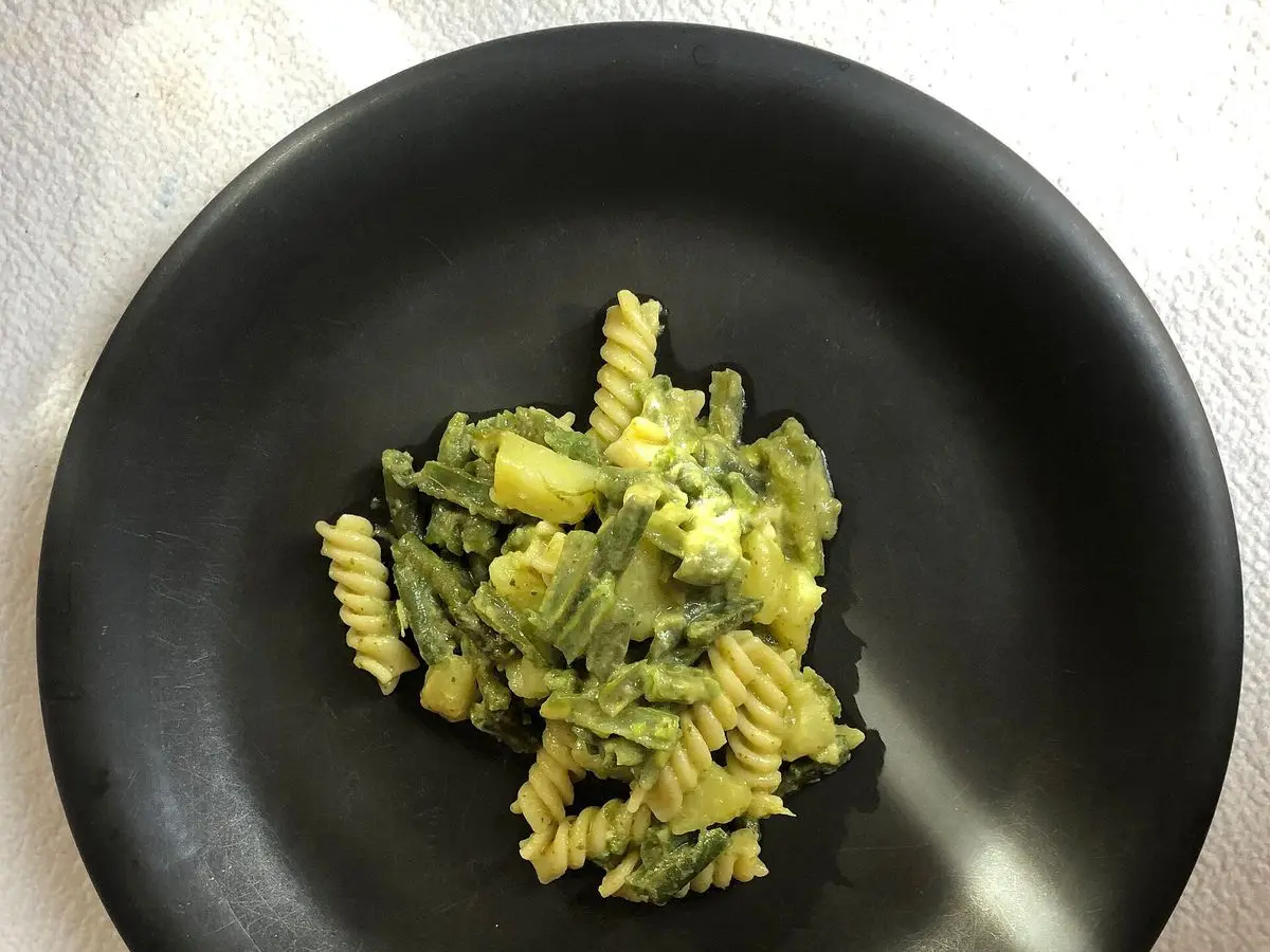 Plato negro con pasta fusilli, judías verdes y salsa pesto verde