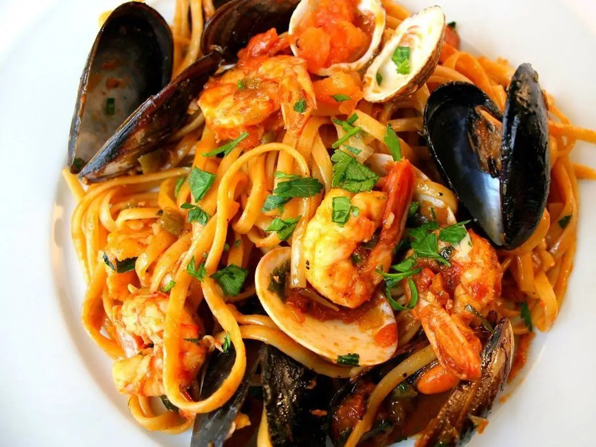 Espaguetis con salsa de tomate, mejillones, almejas y gambas en un plato blanco