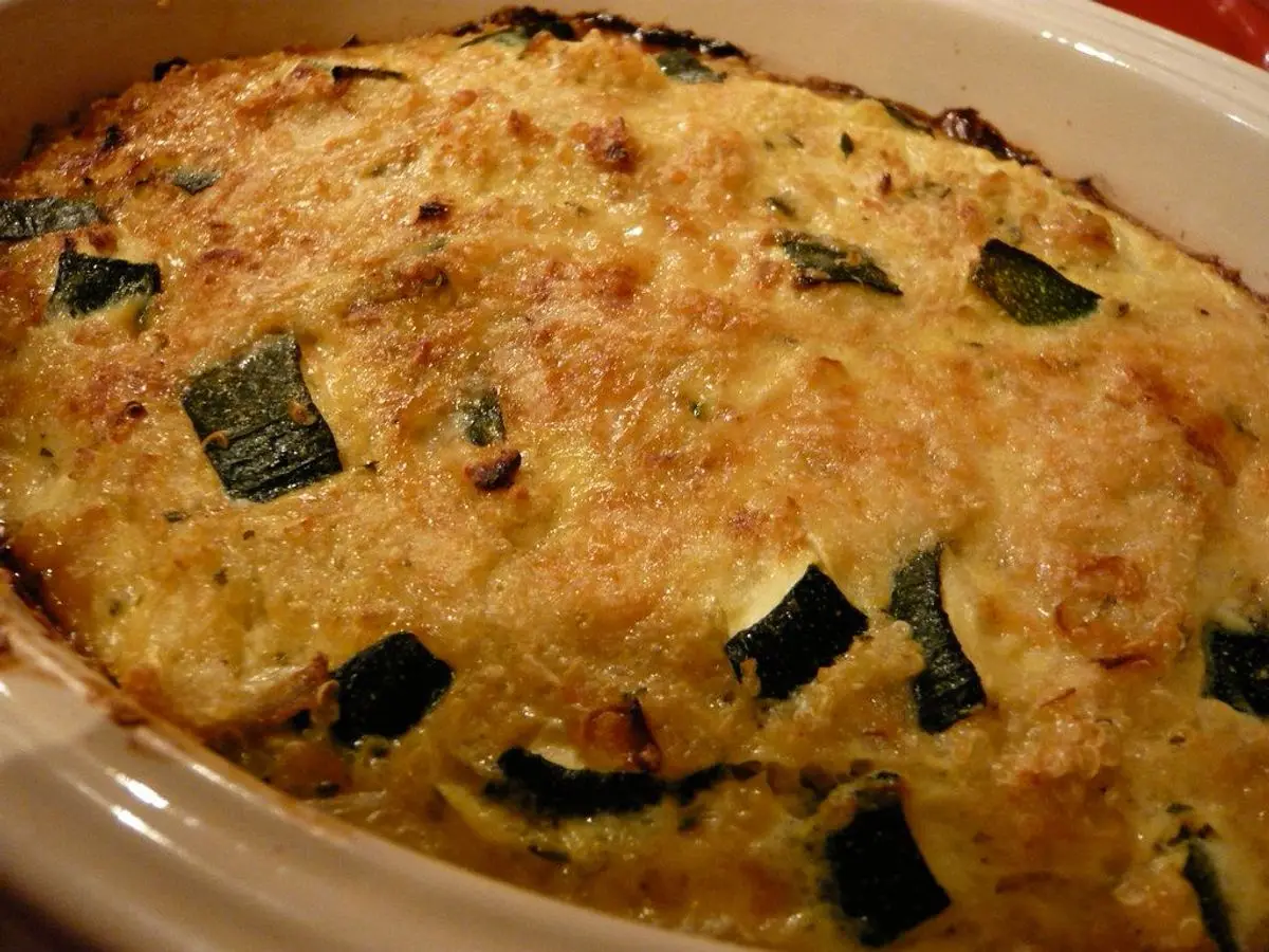 Fuente de horno con pastel gratinado de calabacín y queso con trozos de piel verde visibles