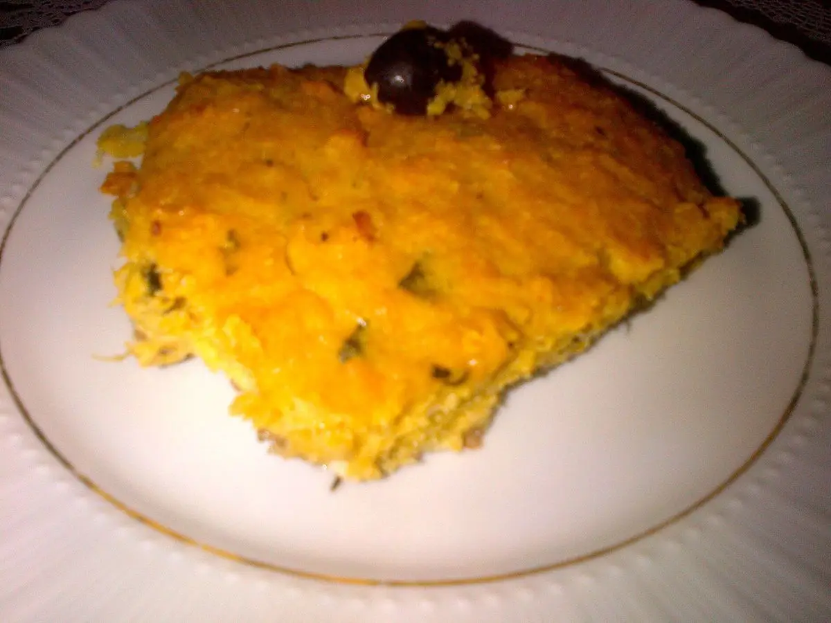Porción de pastel de maíz gratinado dorado en un plato con una aceituna negra encima