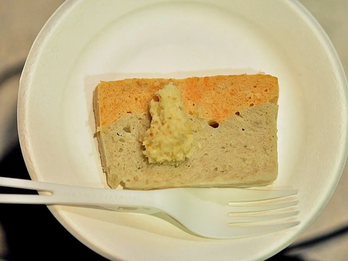 Rebanada de pastel de pescado frío con salsa verde en un plato blanco con tenedor