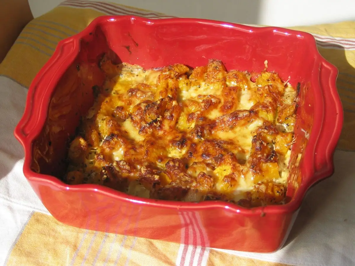 Fuente roja de horno con gratinado de calabaza dorado y queso fundido