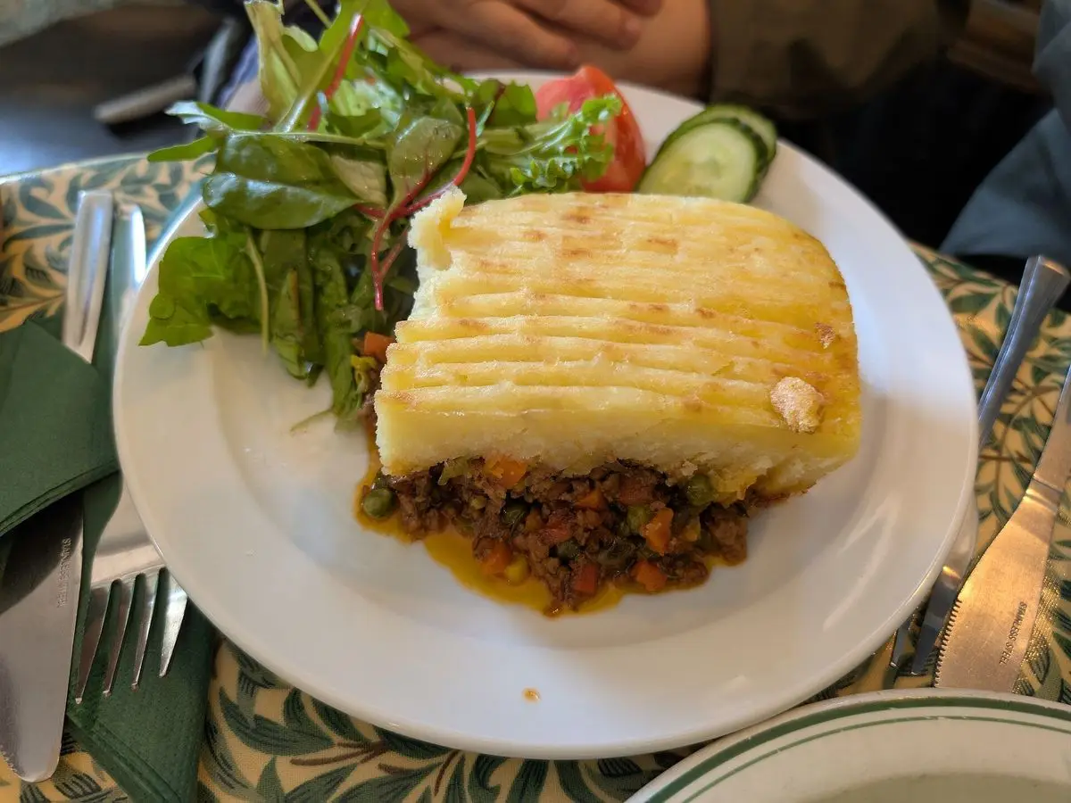 Porción de pastel de pastor con carne picada y capa de puré de patata gratinado, con ensalada
