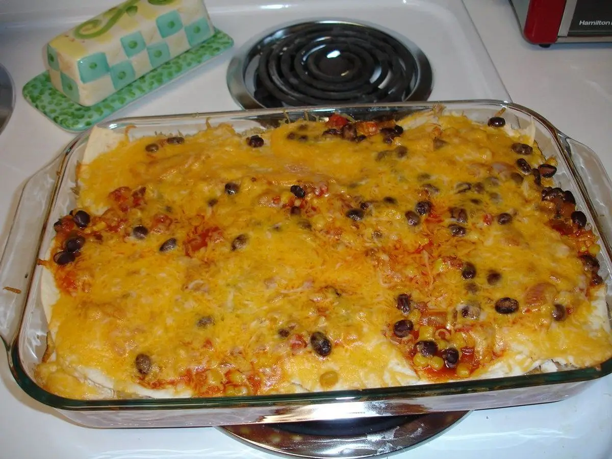 Fuente de cristal con pastel gratinado de tortillas, queso fundido y alubias negras