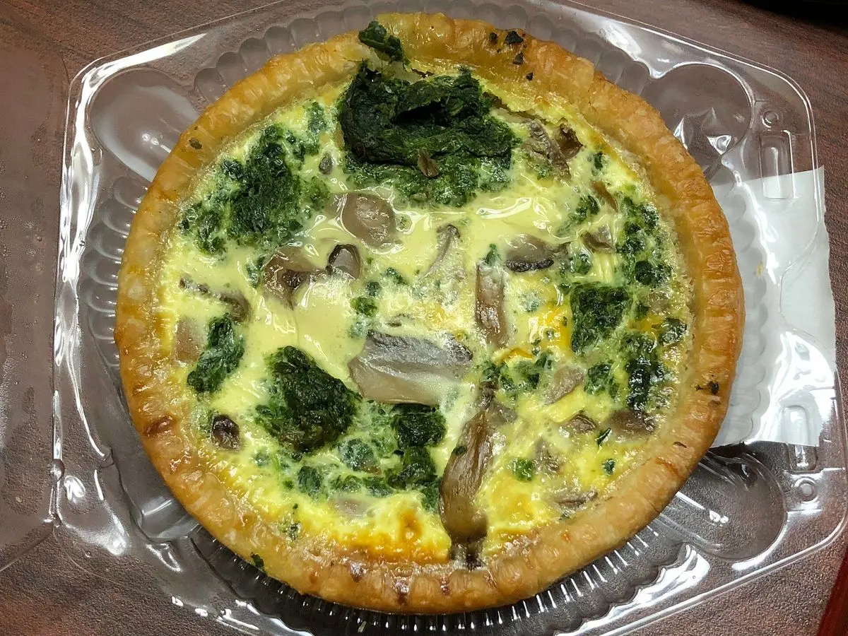 Pastel salado horneado con espinacas y champiñones sobre una base de masa dorada