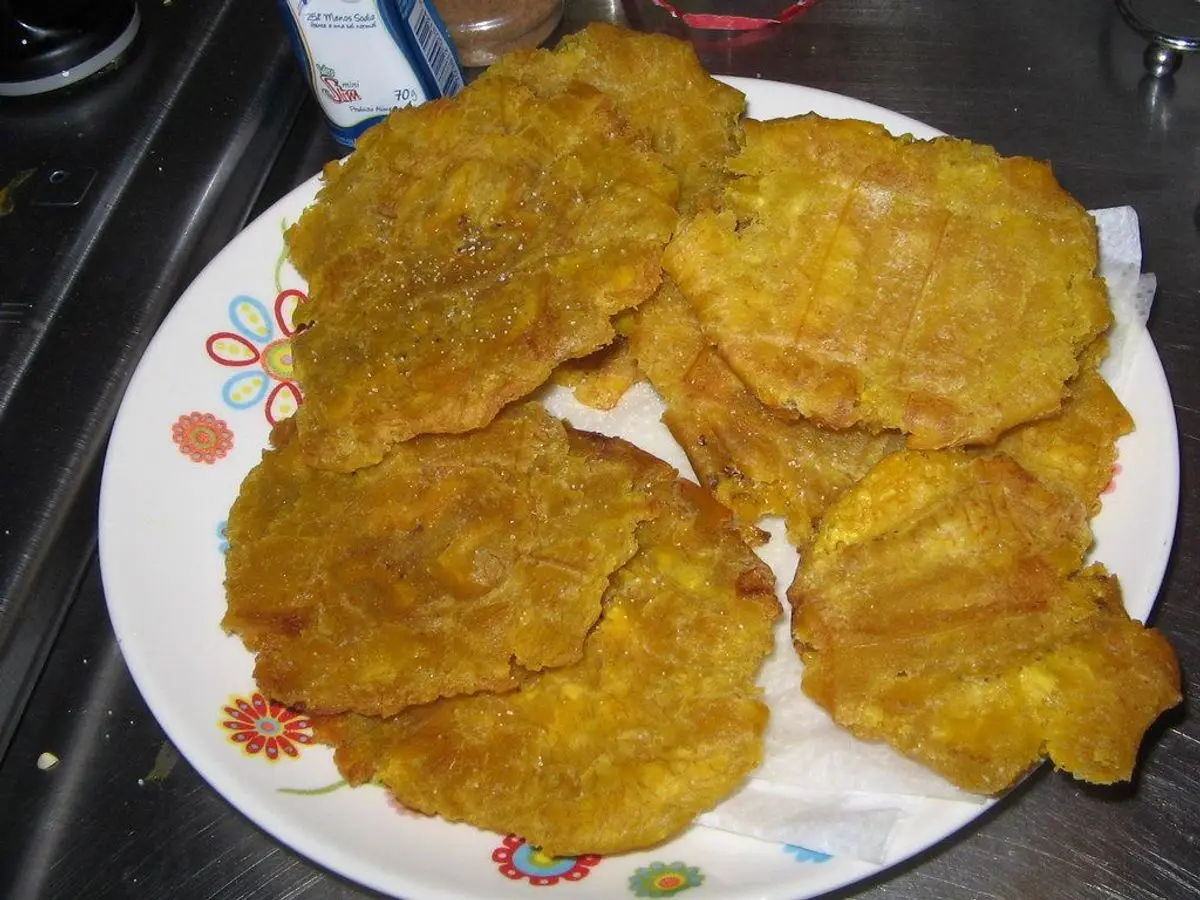 Plato blanco con patacones de plátano macho fritos, aplastados y dorados