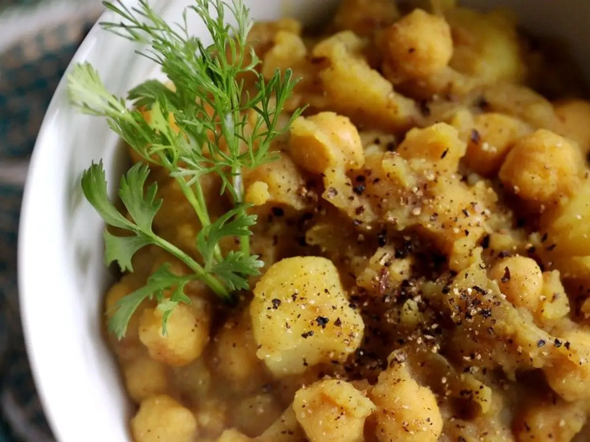 Plato de garbanzos guisados con patata y una ramita de eneldo
