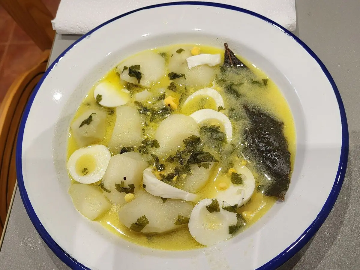 Plato hondo de patatas guisadas en caldo verde con perejil, rodajas de huevo cocido y laurel