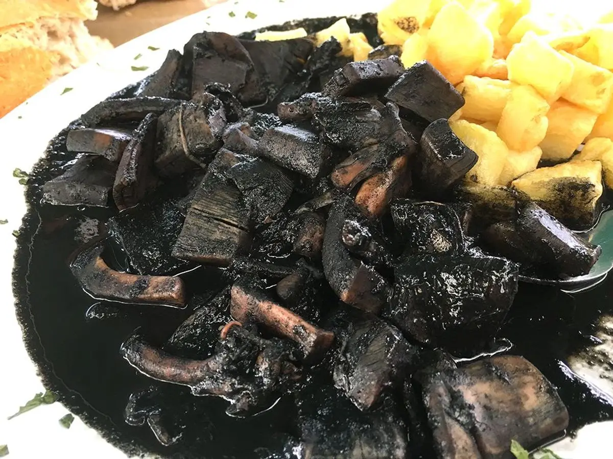 Calamares en su tinta con patatas en un plato