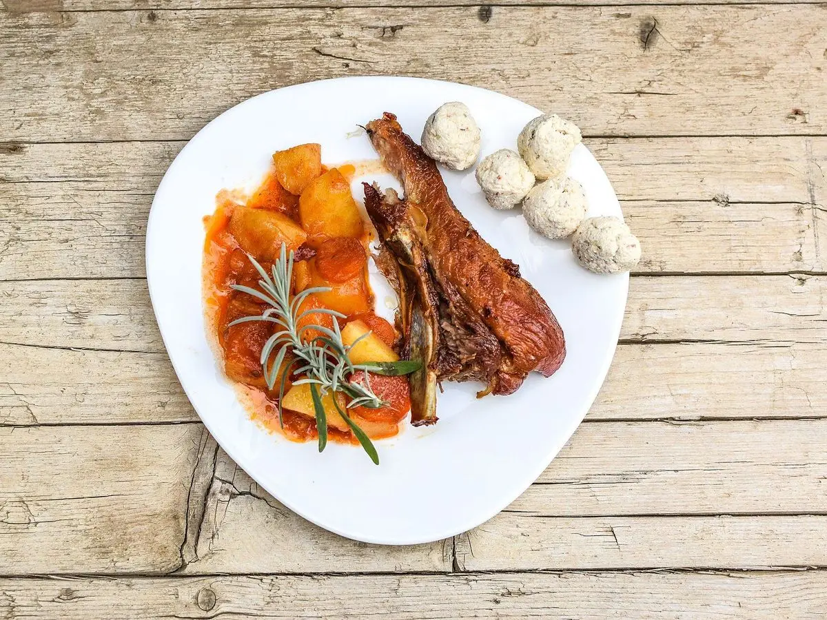 Plato con costilla de cerdo, patatas y zanahoria guisadas con setas y romero