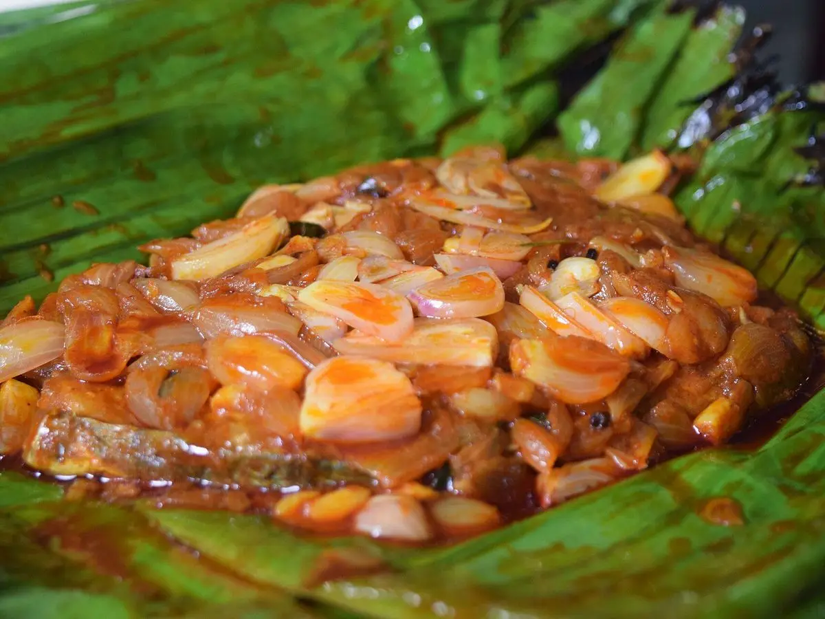 Pescado cocinado envuelto en hoja de plátano con cebolla pochada y especias