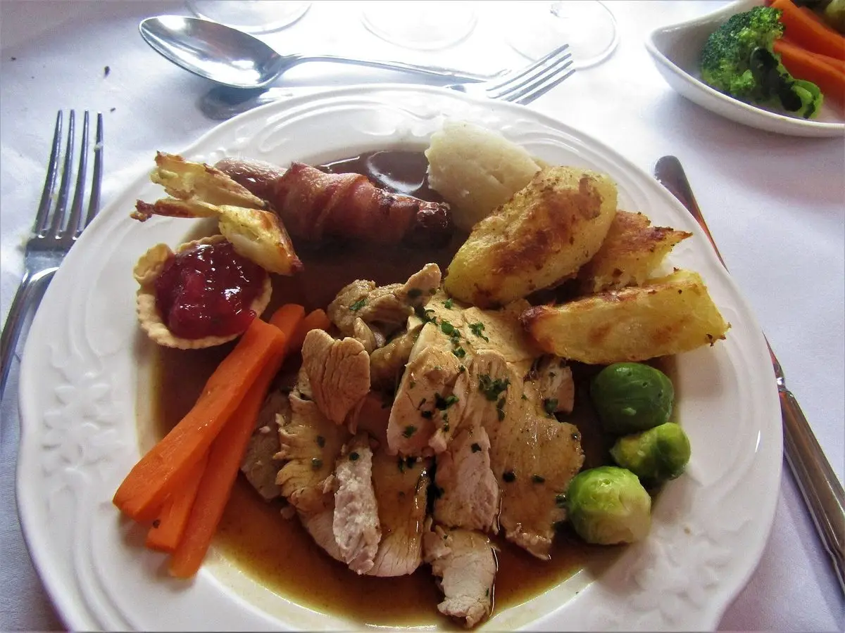 Plato con pavo asado en lonchas, relleno, zanahoria, coles de Bruselas y patatas asadas con salsa