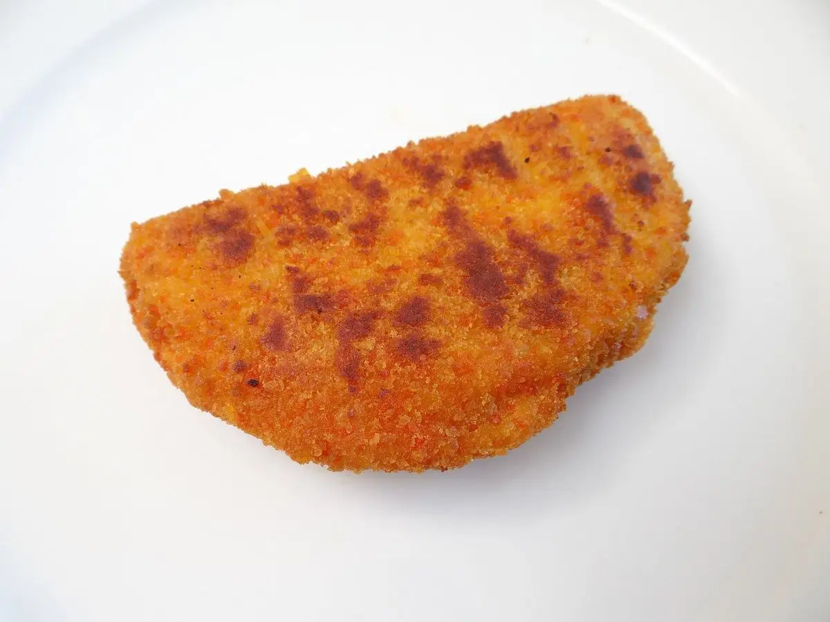 Filete de pollo relleno y empanado, dorado, sobre un plato blanco