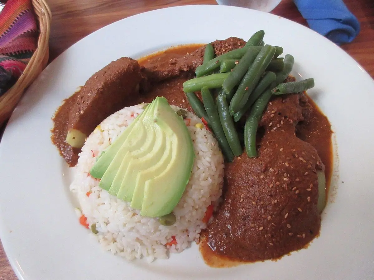 Pepián guatemalteco con judías verdes, aguacate y arroz blanco en un plato