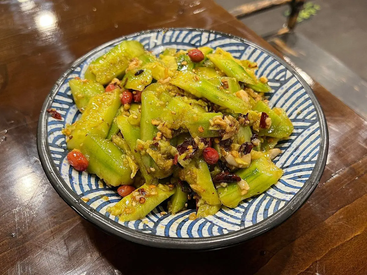 Plato con pepino aplastado a la china aliñado con guindilla y aceite rojo, en un cuenco azul estampado