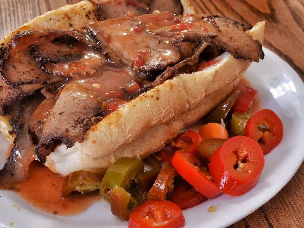 Bocadillo de ternera en lonchas con pimientos verdes y rojos en rodajas y salsa en un plato