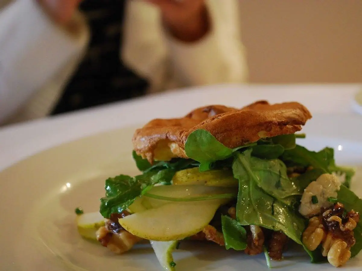 Plato con pera, rúcula, nueces y queso azul con un hojaldre dorado