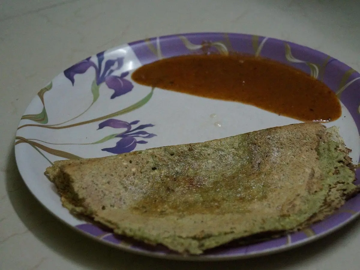 Crepe verde de legumbre sobre plato decorado con salsa roja