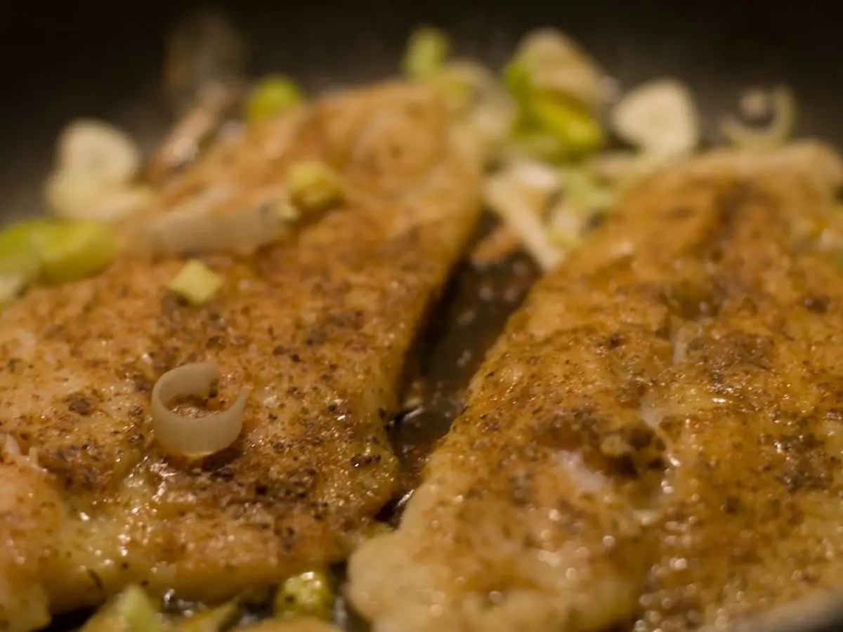 Dos filetes de pescado blanco dorados al horno con cebolleta picada por encima