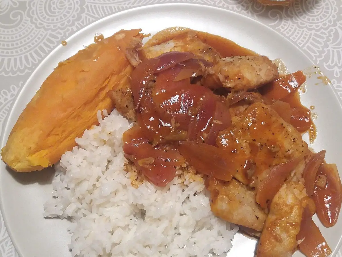 Plato de pescado en escabeche con cebolla roja en salsa, acompañado de arroz blanco y camote