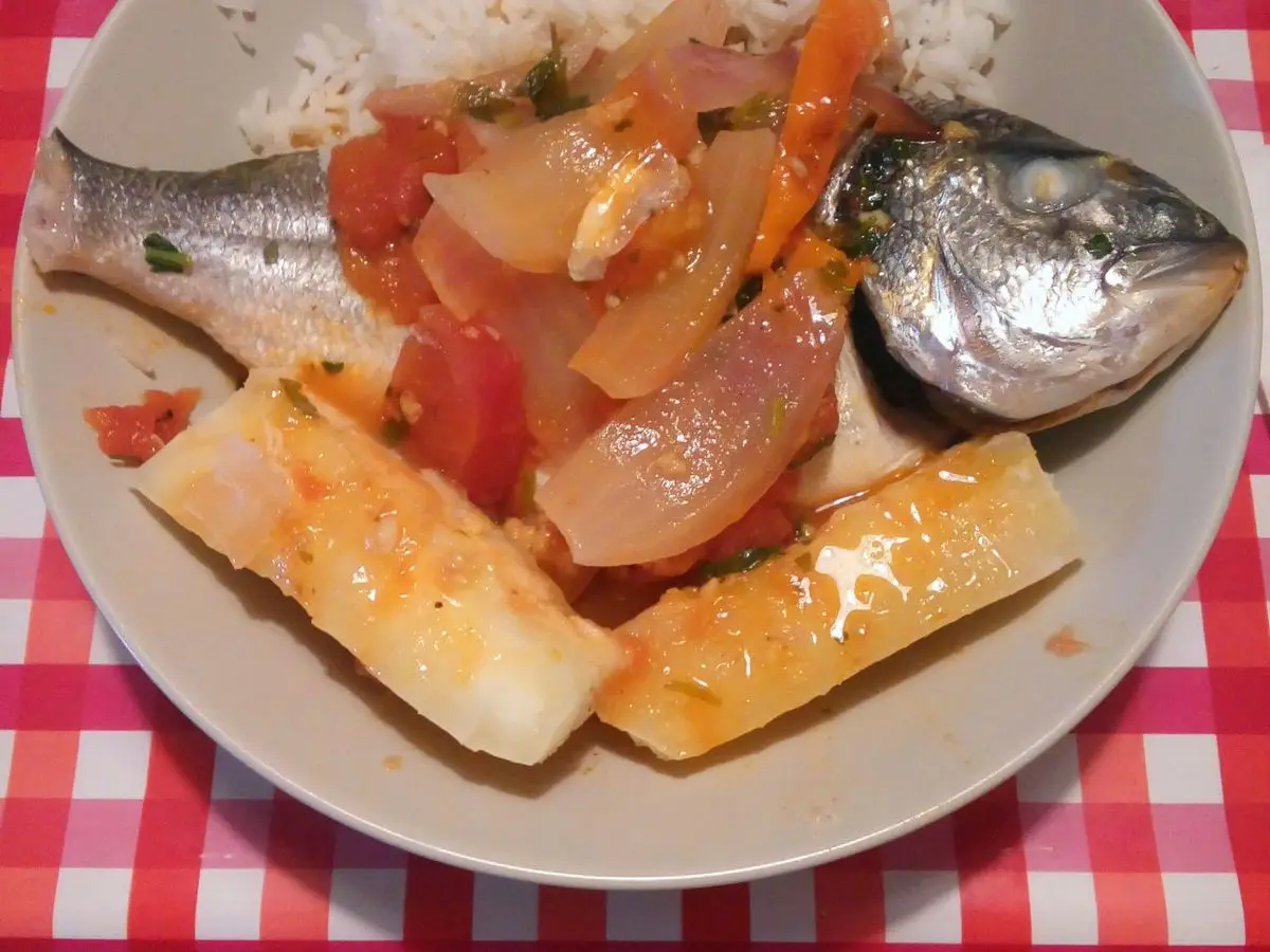 Dorada entera guisada con tomate, cebolla y trozos de yuca, acompañada de arroz blanco