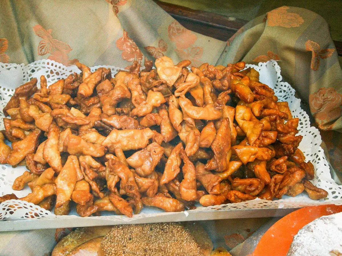 Bandeja con muchos pestiños dorados y brillantes, dulce tradicional, sobre un blonda de papel