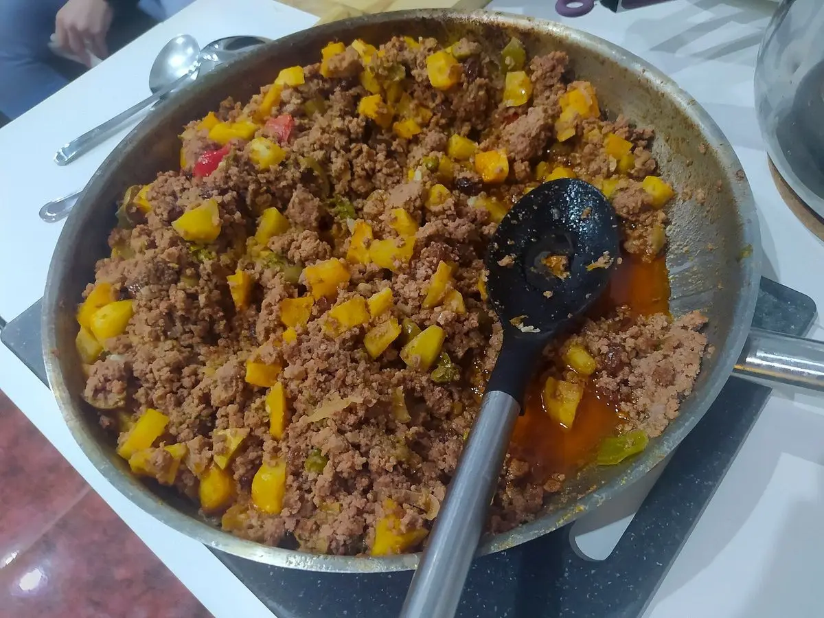 Sartén grande de carne picada guisada con trozos de pimiento y tomate