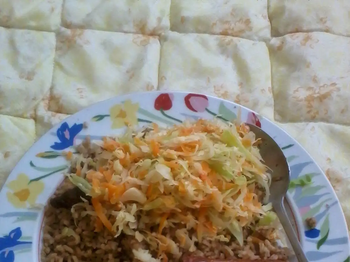 Plato de arroz pilau especiado con una salchicha de ternera y ensalada de repollo y zanahoria