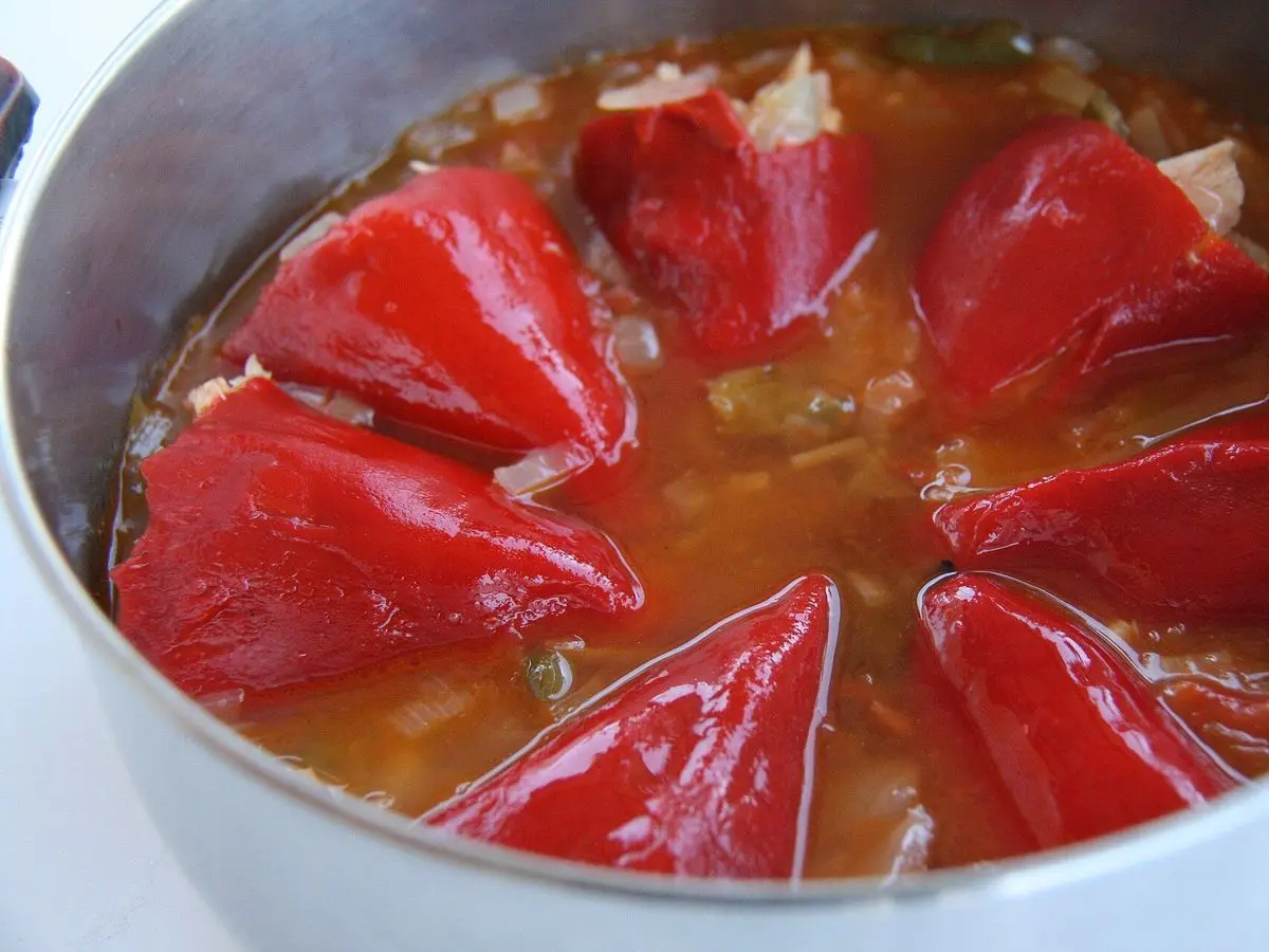 Pimientos rojos del piquillo rellenos guisados en salsa dentro de una cazuela