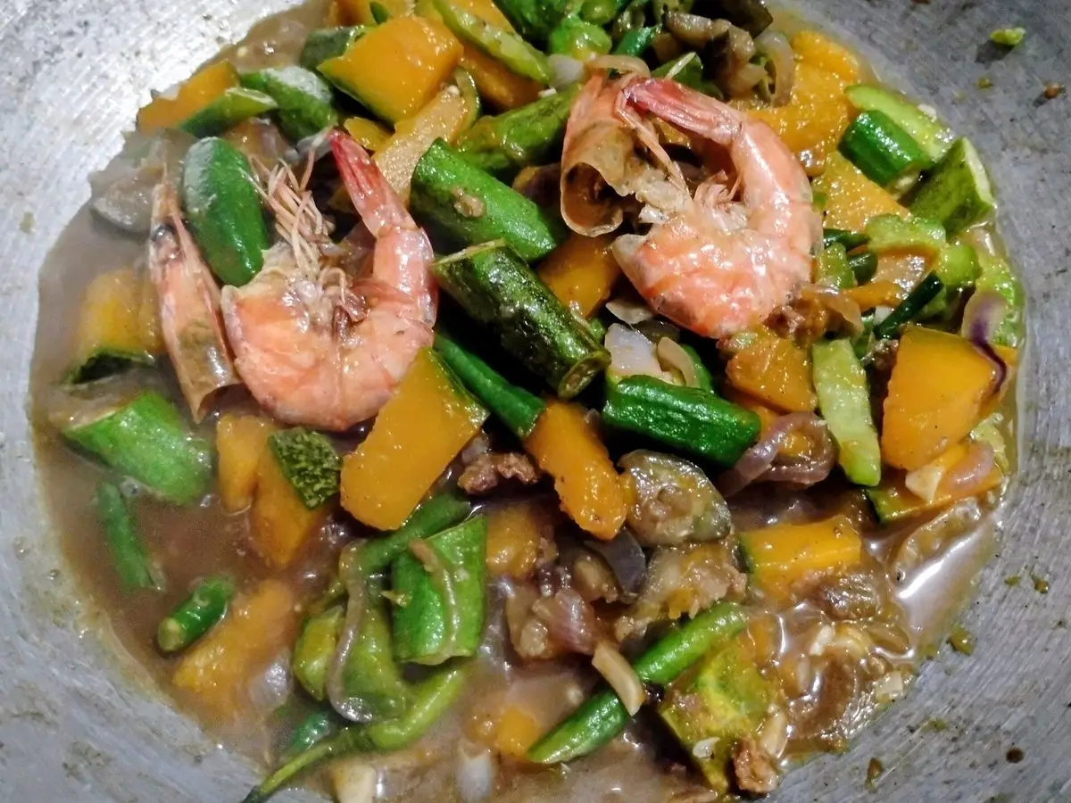 Guiso de calabaza, okra, judías verdes y gambas enteras en una sartén