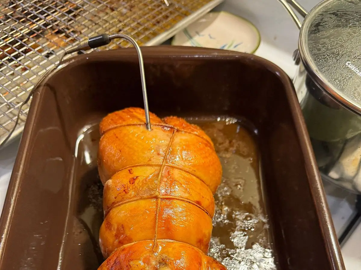 Pintada rellena asada, dorada y brillante, en una bandeja de horno