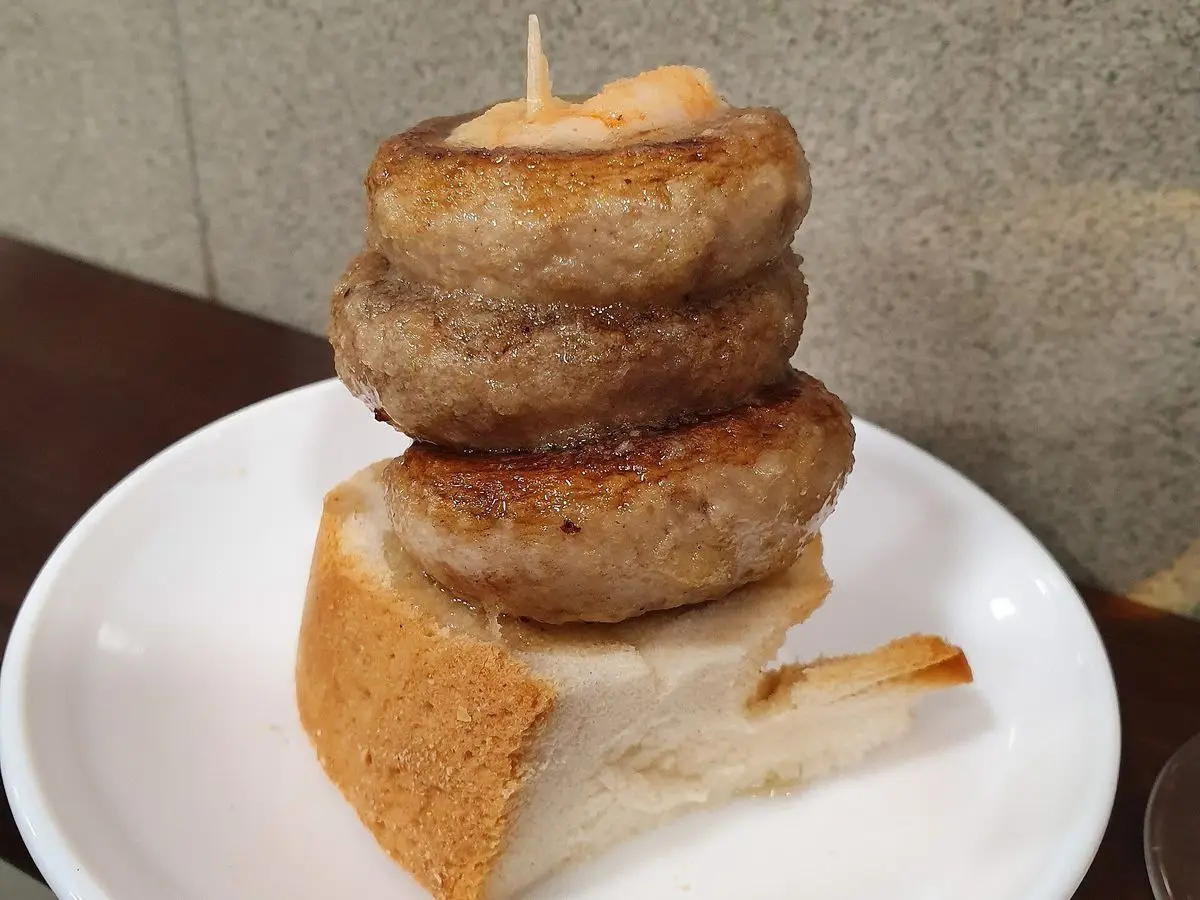 Pincho de champiñones a la plancha apilados sobre una rebanada de pan en un plato blanco, en Logroño