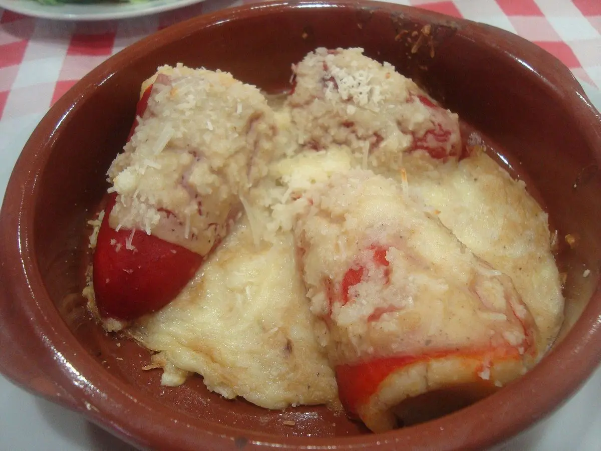 Cazuela de barro con pimientos del piquillo rellenos y cubiertos de salsa blanca gratinada