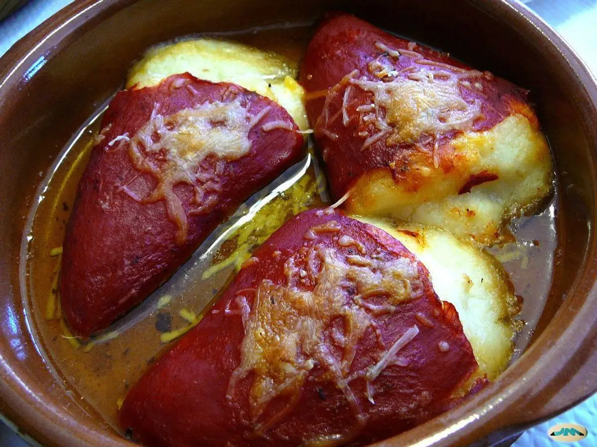 Pimientos del piquillo rellenos y gratinados con queso en una cazuela de barro