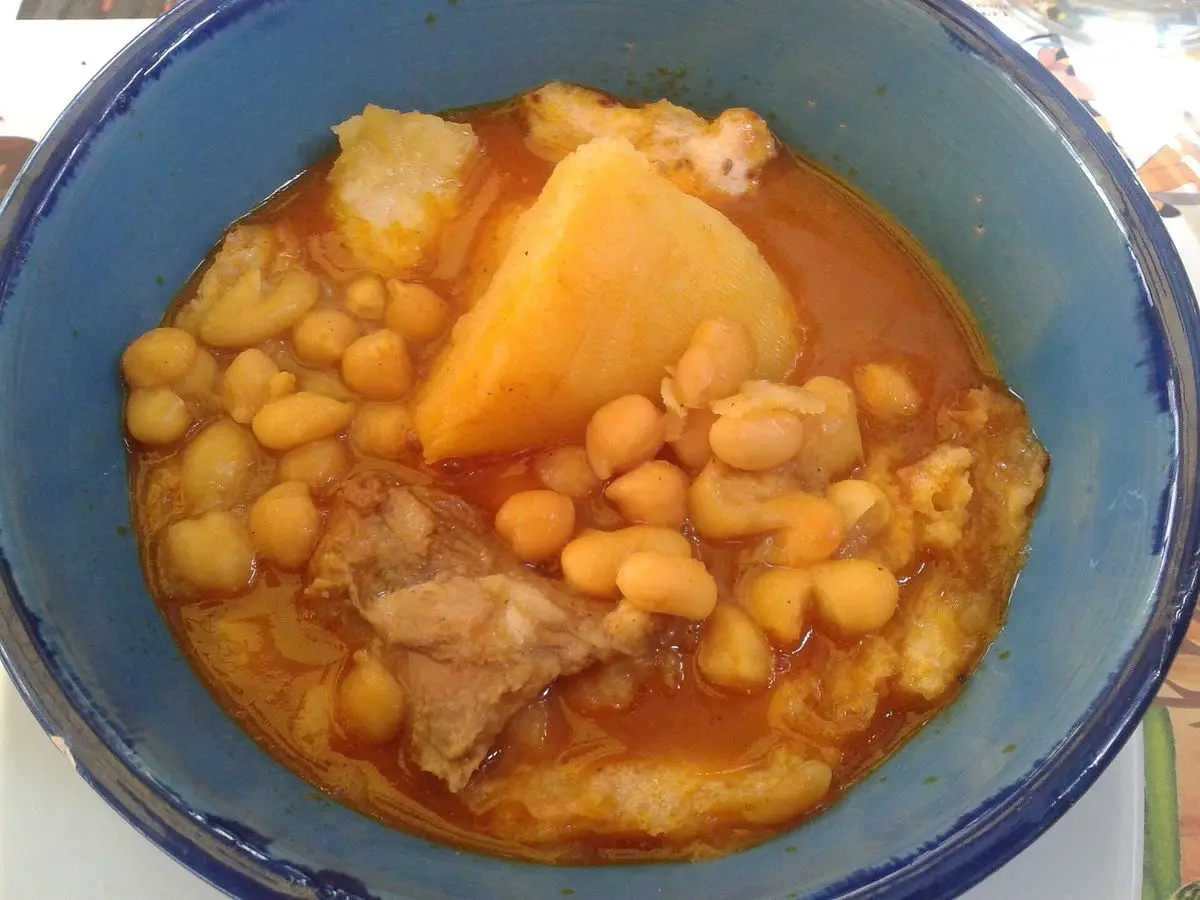 Cuenco azul de guiso de cordero con garbanzos y patata en caldo anaranjado