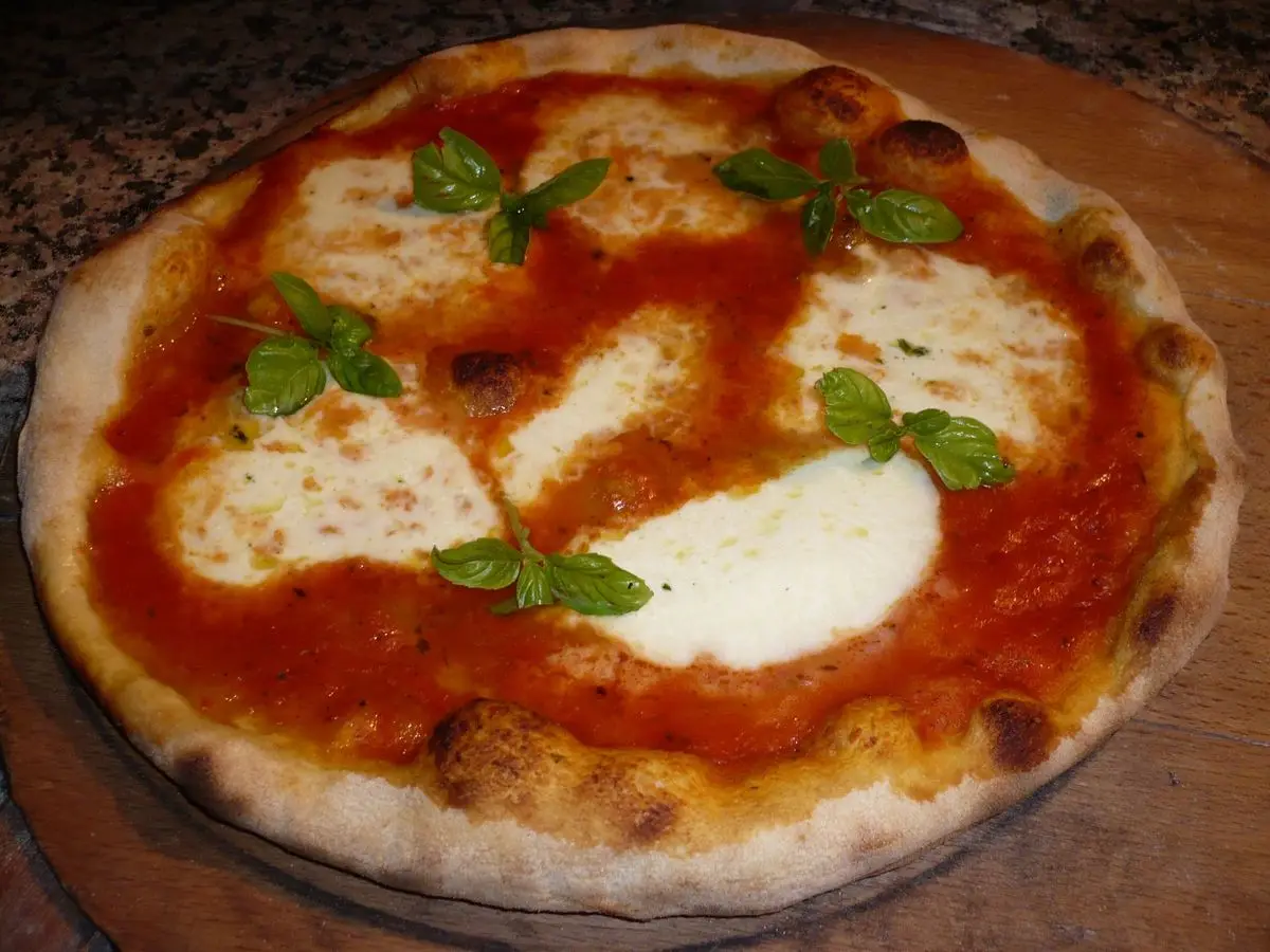 Pizza margarita con salsa de tomate, mozzarella fresca y hojas de albahaca