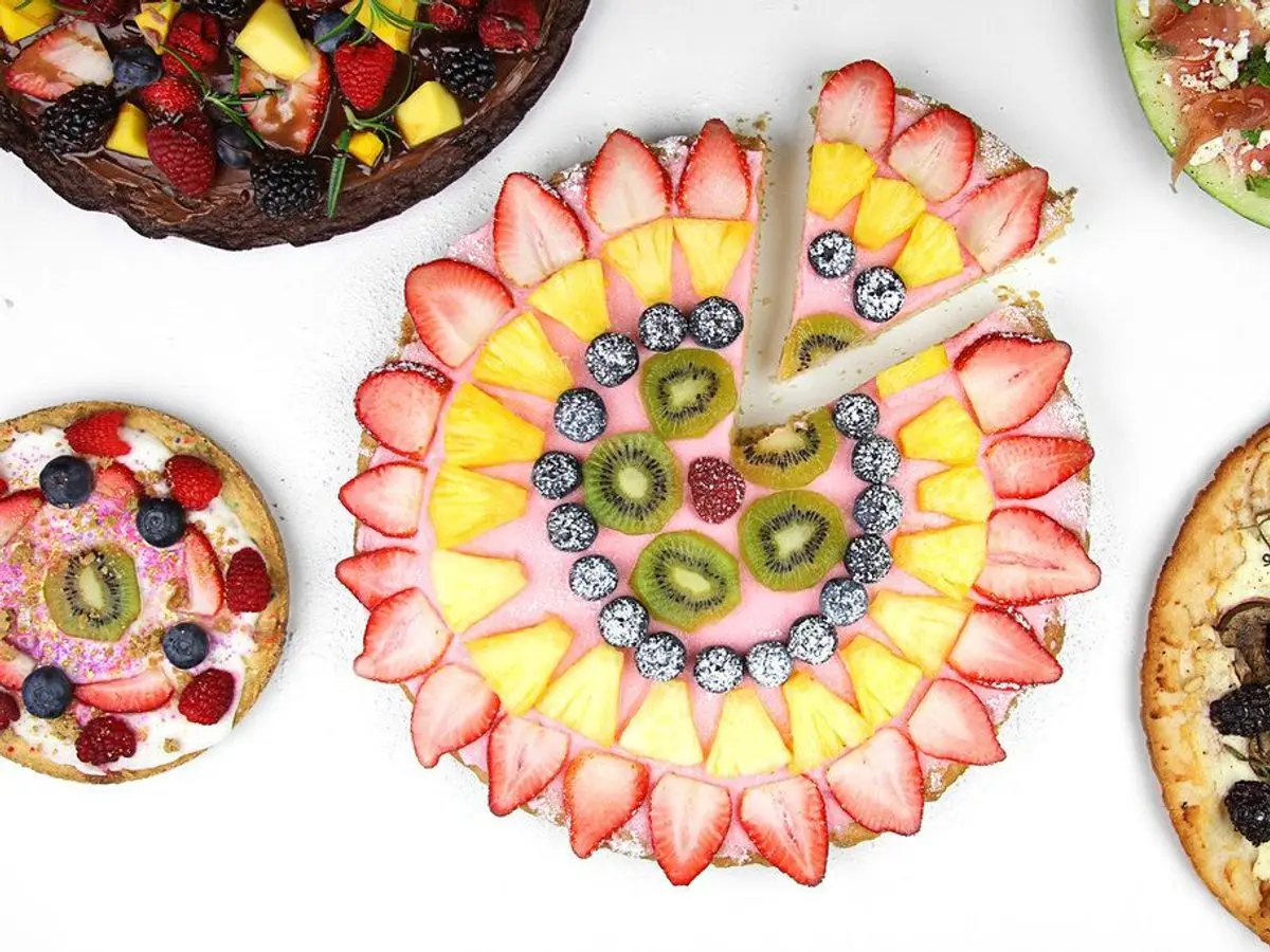 Pizzas de fruta con fresas, kiwi y frutas de colores dispuestas en círculos sobre fondo blanco