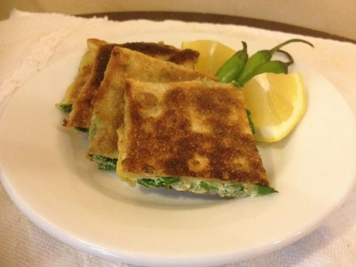Murtabak, masa fina doblada y rellena de carne y huevo, cortada en cuadrados con limón y guindilla