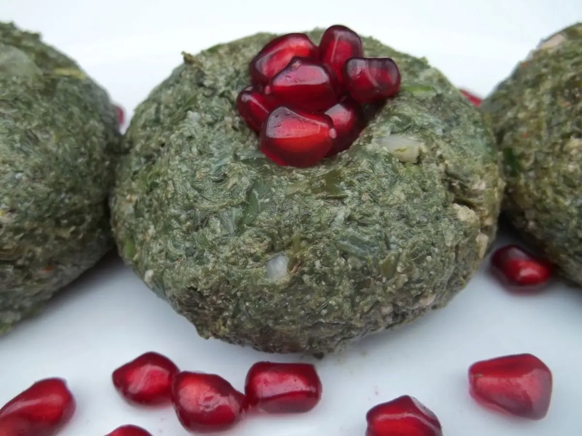 Bolas de pkhali georgiano de espinacas y nueces decoradas con granos de granada sobre fondo blanco
