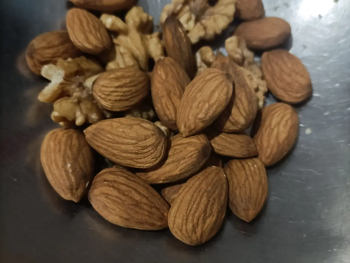 Puñado de almendras y nueces sobre una superficie metálica