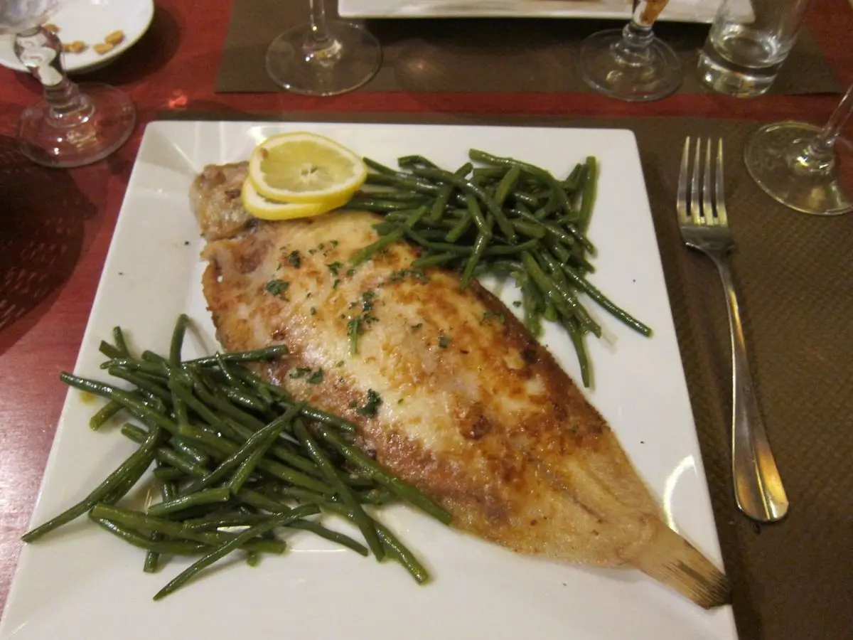Lenguado a la meunière con limón, patatas y verduras en un plato