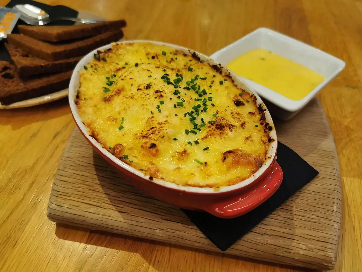 Cazuela roja de plokkfiskur gratinado con cebollino, salsa amarilla y pan de centeno tostado