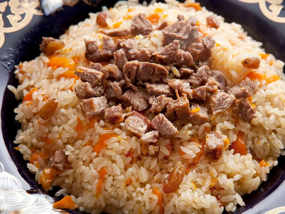 Pilaf de arroz con trozos de carne y zanahoria en tiras en un cuenco decorado