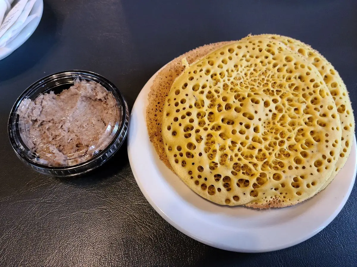 Ploye, torta fina de trigo sarraceno con burbujas, en un plato junto a un cuenco con untable