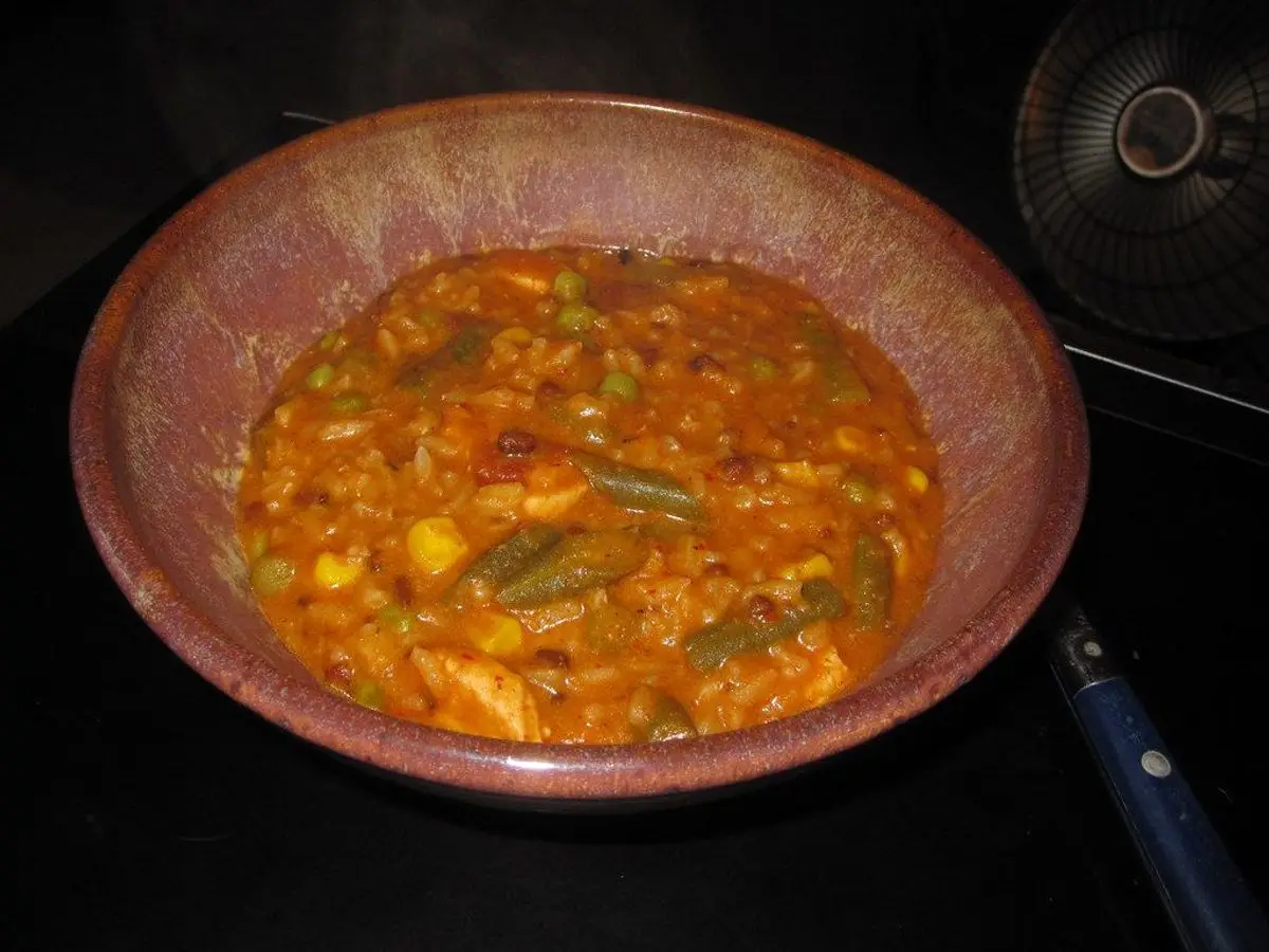 Cuenco de barro con guiso de legumbres y verduras en salsa de tomate